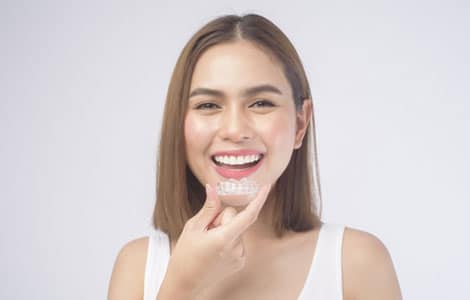 Smiling woman touching her teeth against white background for dental care website